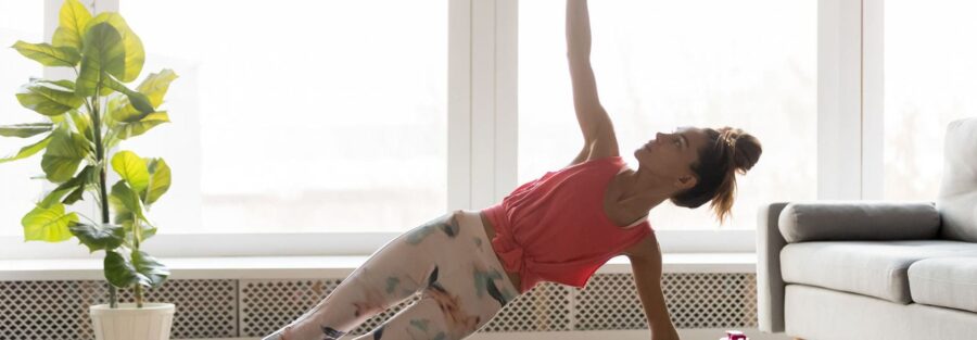 Mujer en un estudio de pilates, realizando un ejercicio de equilibrio en la colchoneta para mejorar la postura.